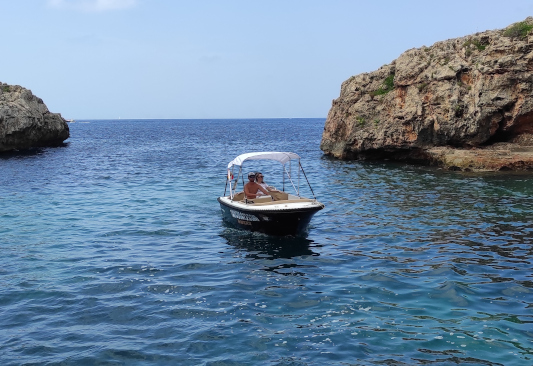 Barco sin licencia para alquilar en Ciutadella de Menorca. El barco es de color negro con un toldo de color blanco
