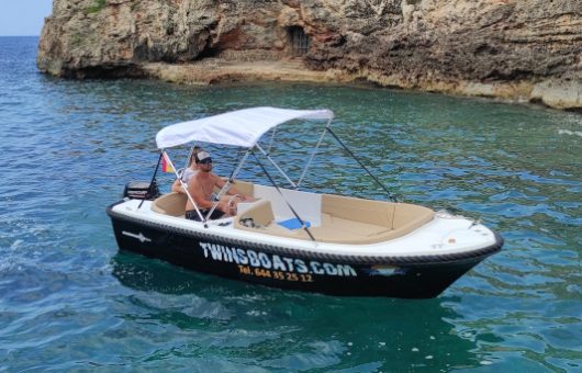 Barco sin licencia para alquilar en Ciutadella de Menorca. El barco es de color negro con un toldo de color blanco